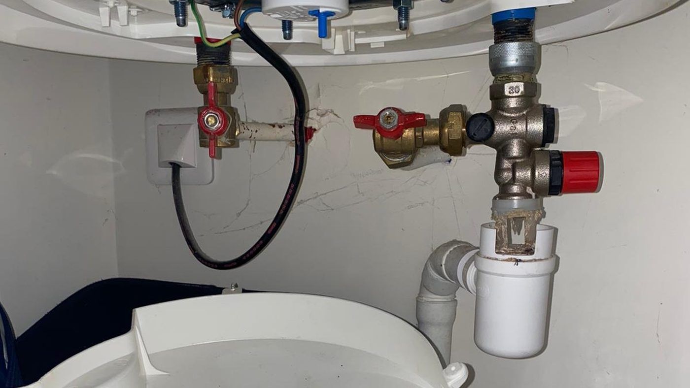 Siphon d'évacuation sous le groupe de sécurité d'un chauffe-eau, source d'odeur d'égout identifiée par La Tuyauterie Française en Île-de-France